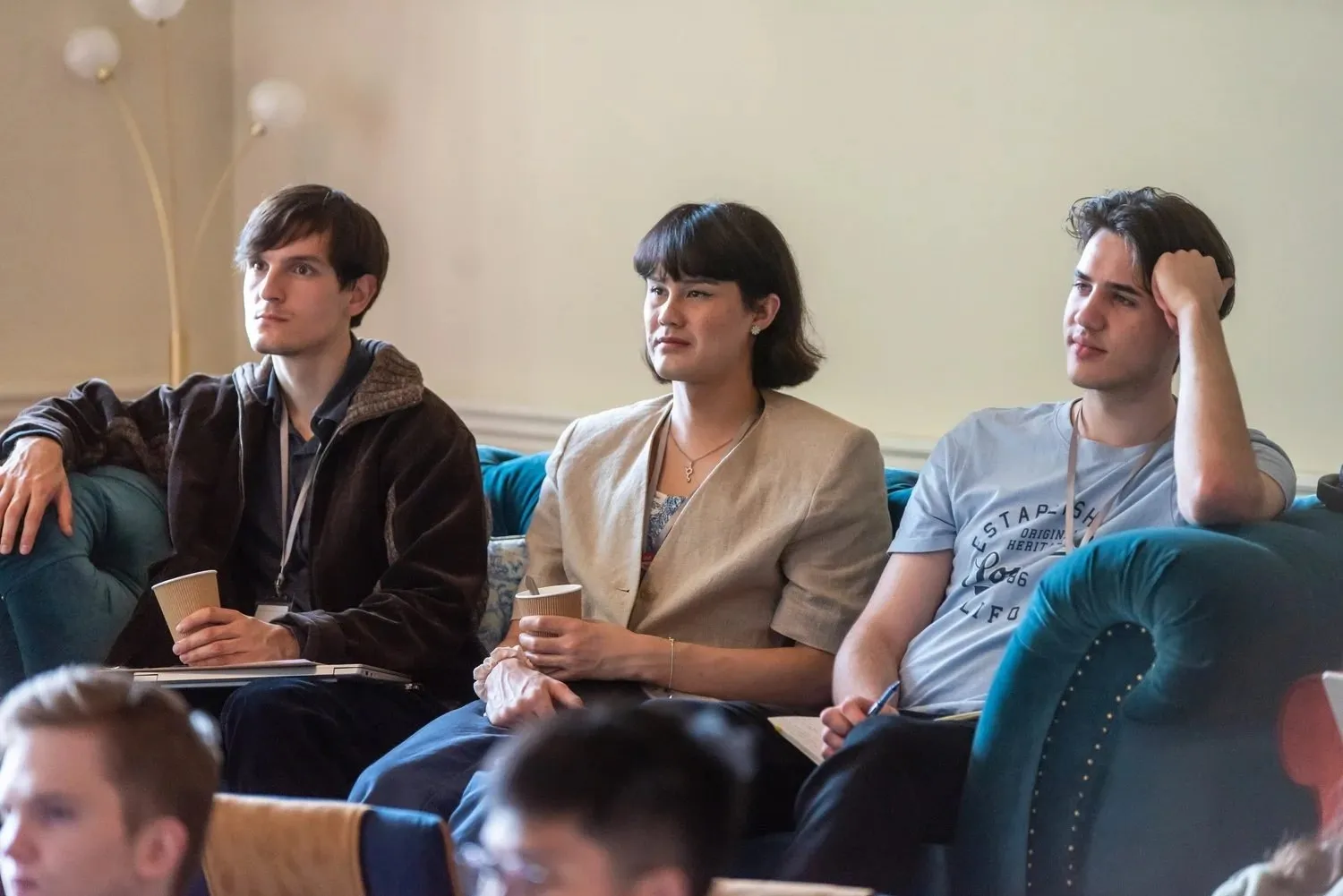 Three attendees on a sofa listening during a session