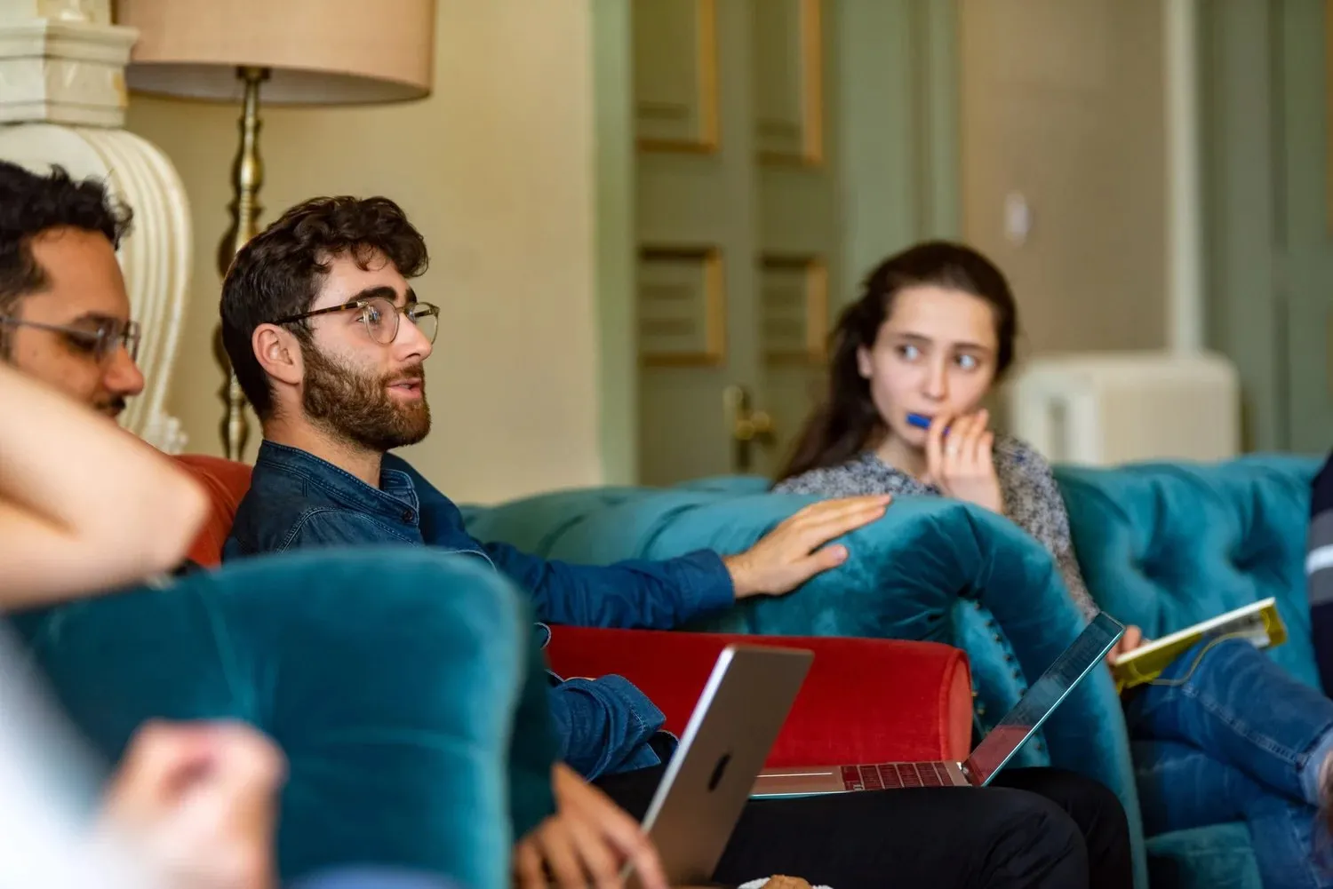 Three attendees in conversation on a sofa, one gesturing as she talks
