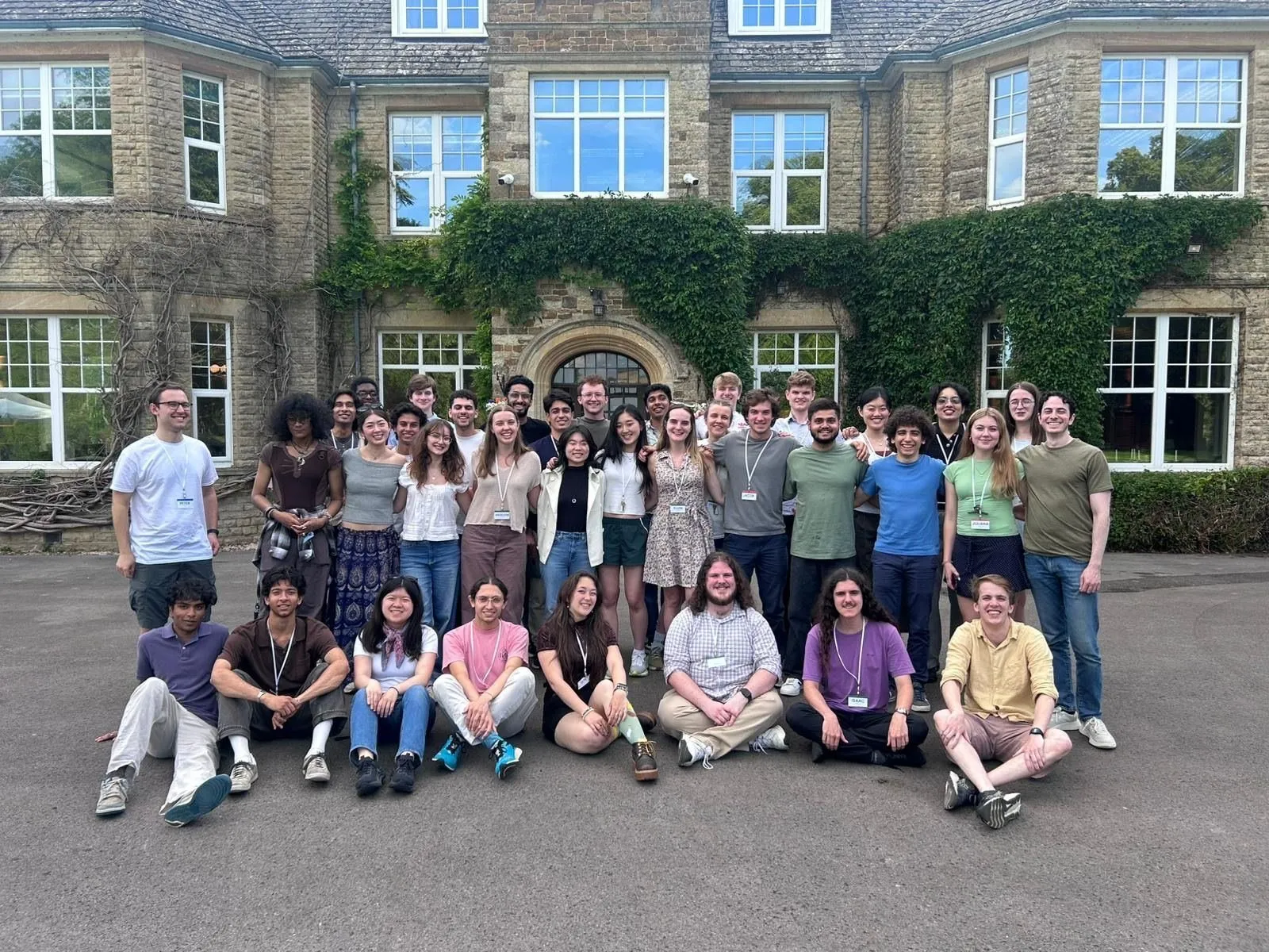 A workshop cohort gathered in front of an ivy-covered manor house