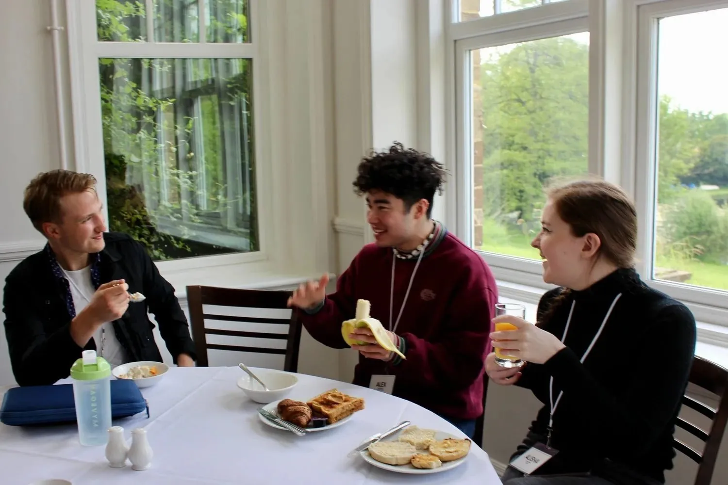 Three attendees talking over breakfast by a window